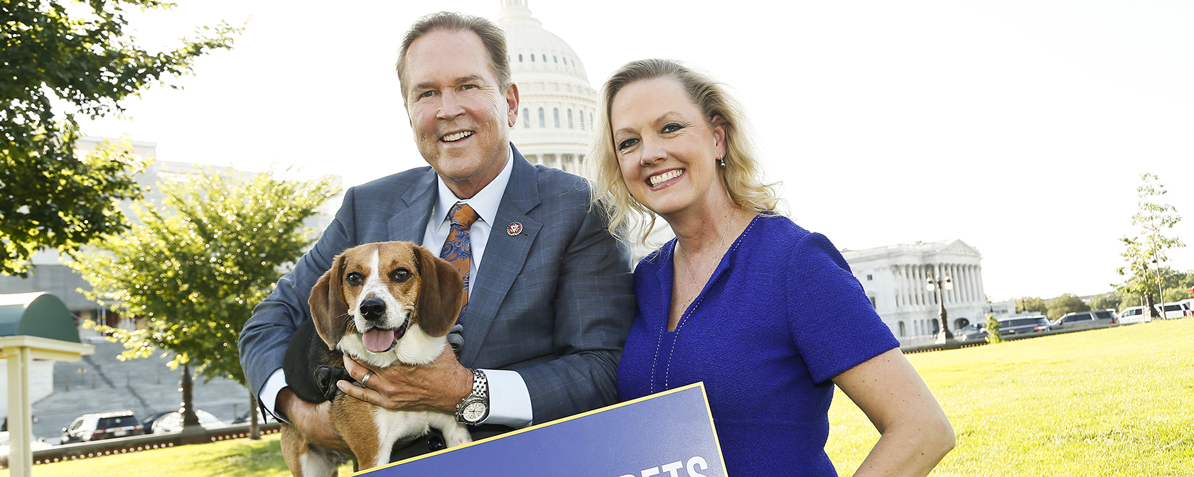 man and a women stand in front of the U.S. Capitol holding a beagle