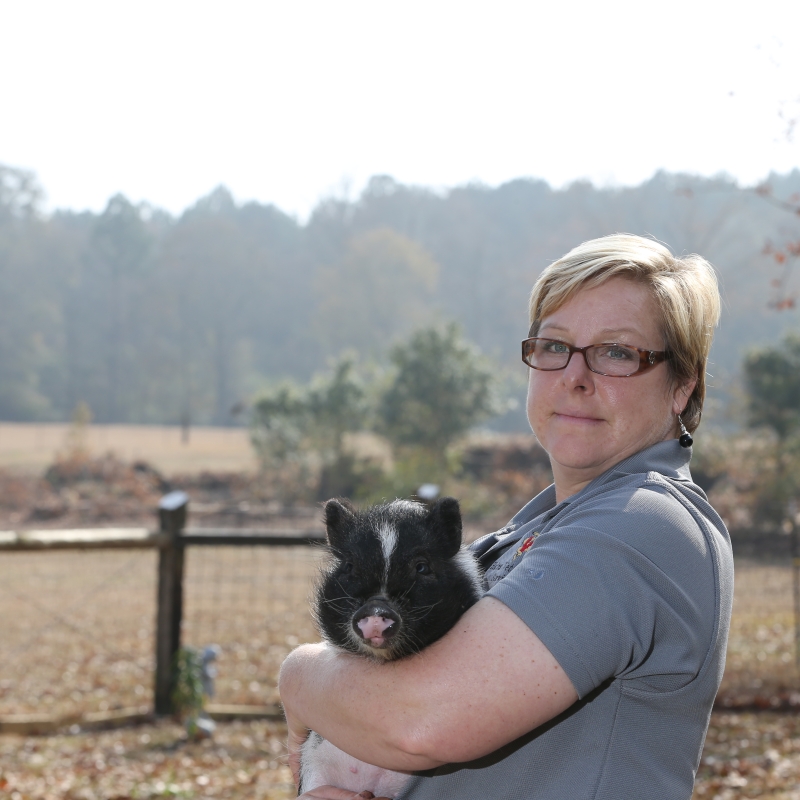 Person holding farm animal.